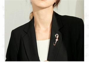 Macro shot of large safety pin brooch with rose gold plating and crystal inlay on a blazer