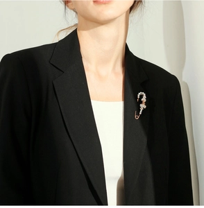 Detailed view of large rose gold safety pin brooch with crystals on a black suit lapel