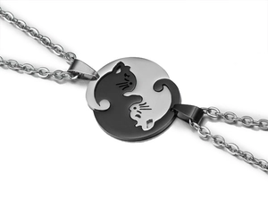 Macro shot of interlocking black and silver cat couple pendant necklaces in stainless steel