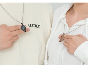Detail of heart puzzle necklaces for couples in black and silver with LOVE engraving