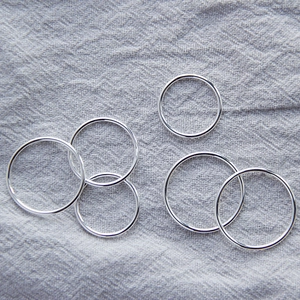 Set of five minimalist S925 sterling silver thin band rings displayed on linen fabric