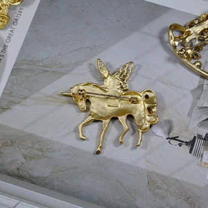Detail view of the back of a matte gold unicorn brooch with sturdy metal pin fastener