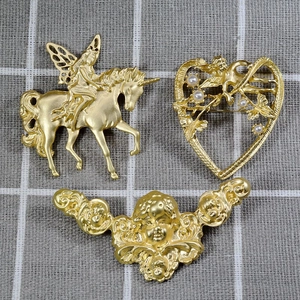 Three vintage matte gold brooches featuring fairy unicorn and angel designs on fabric