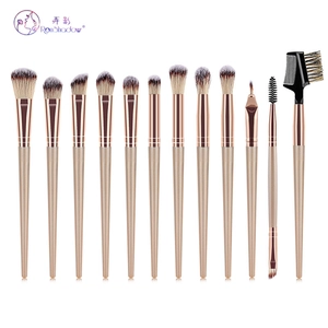 Flat lay of 12-piece champagne gold makeup brush set with soft grey gradient bristles