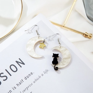 Cat and star charms on shell moon earrings displayed on a white decorative tray