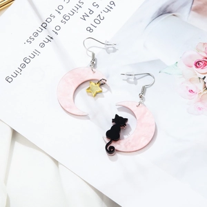 Detailed view of asymmetric pink crescent moon earrings with black cat and gold star