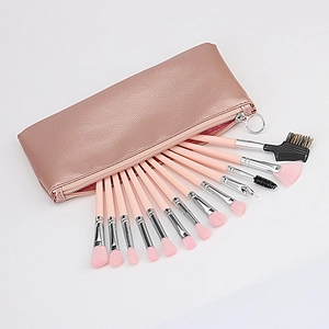 Close-up of pink makeup brushes with synthetic bristles and a matching metallic pink bag