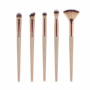 Detailed set of 5 professional makeup brushes with champagne gold handles on white background