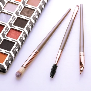 Close-up of eye shadow palette and rose gold makeup brushes on white background