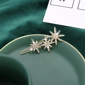 Macro detail of golden star hair clip with crystals on green velvet background
