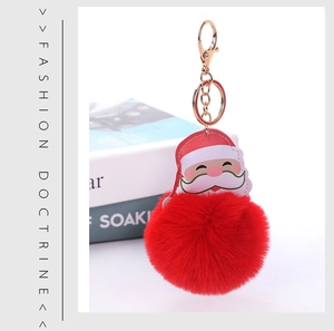 Detail view of a fluffy red pom-pom keychain with Santa Claus face and golden clasp