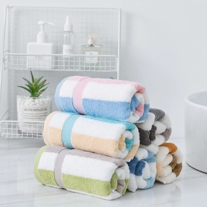 Thick cotton striped towels stacked on a white shelf in a minimalist bathroom setting