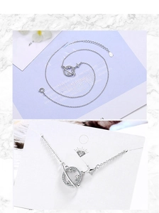 Close-up of s925 silver planet necklace with zircon stones on a branding display card