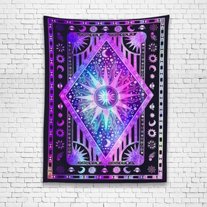Close-up of bohemian tapestry with mystical sun, moon, and celestial stars on a brick wall