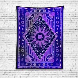 Detail of bohemian sun and moon tapestry with celestial stars on a white brick wall