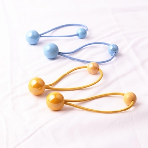 Dettaglio di elastici per capelli azzurri e arancioni con doppie perle su tessuto bianco
