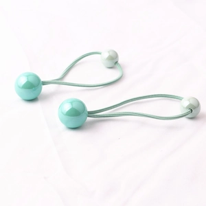 Dettaglio di elastici per capelli verde acqua con doppie perline di varie dimensioni
