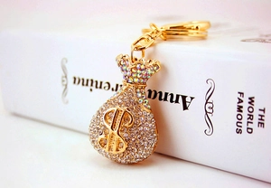 Detail of money bag keychain with crystal rhinestones and gold-plated finish on book