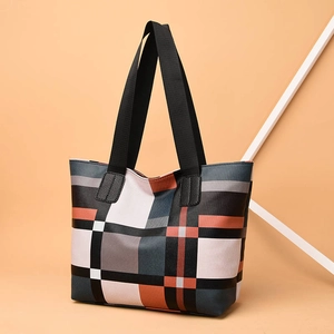 Stylish large capacity plaid tote bag with black handles on warm orange background