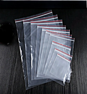 Multiple sizes of clear PE self-sealing storage bags stacked on a black wood texture