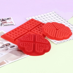 Detail view of red silicone waffle mold with square and heart shapes on checkered cloth