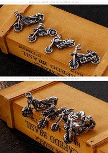 Detailed macro view of four vintage stainless steel motorcycle pendants on a wooden background