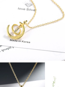 Detailed macro view of a gold planet and moon pendant necklace with zircon stones