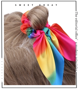 Detail of a rainbow gradient satin scrunchie with a long bow tie on blonde hair