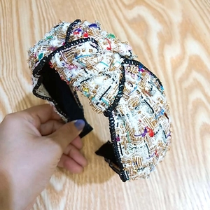 Dettaglio del cerchietto in tweed multicolore con design a nodo largo e trama intrecciata