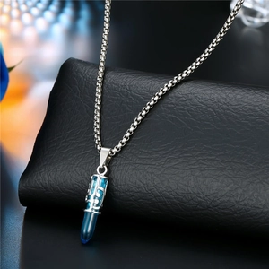 Macro shot of silver filigree capsule pendant with blue crystal on stainless steel chain
