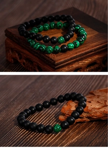 Detail of matte black agate and green malachite beaded bracelets on vintage wood