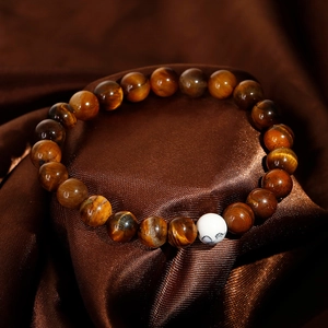 Handmade bracelet with natural tiger eye and turquoise beads on brown silk background