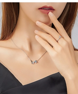 Close-up of elegant bow butterfly necklace and ring set with blue and clear gemstones