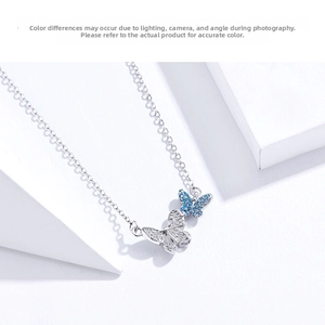 Macro shot of silver bow pendant with detailed metal wings and sparkling blue zircons