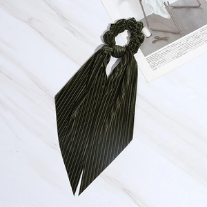 Dark green pleated velvet hair scrunchie with long ribbon bow on marble background