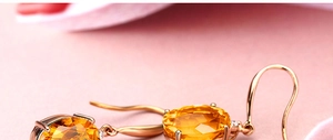 Detailed macro view of oval yellow gemstone earrings with four-prong gold-tone setting