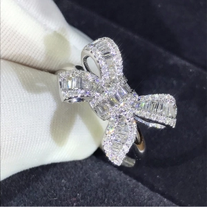 Close-up of a silver bow ring with baguette-cut diamonds on black velvet background