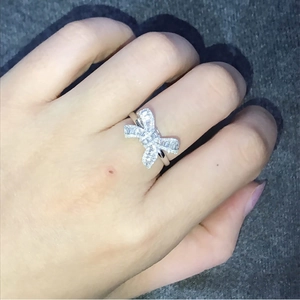Detailed view of silver bow-shaped ring with pavé-set sparkling zircons on hand