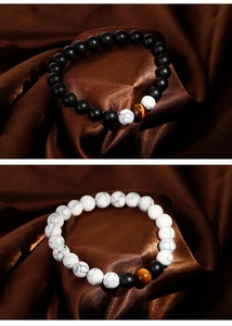 Detailansicht von matten schwarzen Achat- und weißen Marmorarmbändern auf brauner Seide