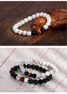 Detail von 8mm matten Onyx- und weißen Türkis-Perlenarmbändern auf Holzuntergrund