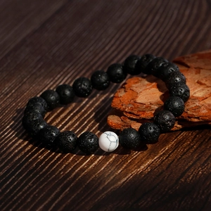 Beaded bracelet with black lava stones and white turquoise on dark rustic wood background
