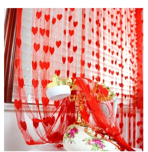 Detail of red heart fringe curtain draped over a vintage phone with tassel accents