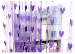 Close-up of purple string curtain with heart patterns hanging in front of a window