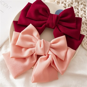 Detailed view of layered fabric bow clips in burgundy and coral chiffon texture