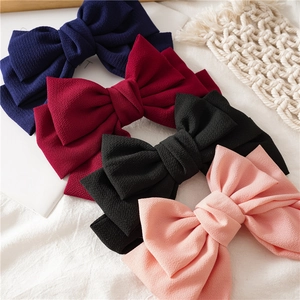 Detailed flat lay of fabric bow hair clips in navy blue, burgundy, black, and pink colors