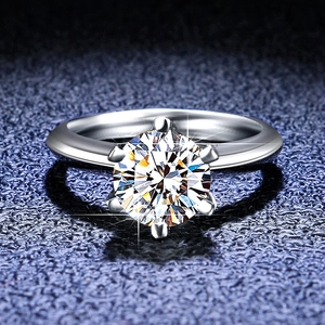Macro detail of a classic six-prong moissanite setting on a polished silver ring band