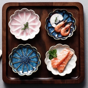 Macro view of petal-shaped ceramic dipping sauce dishes on a dark wooden tray