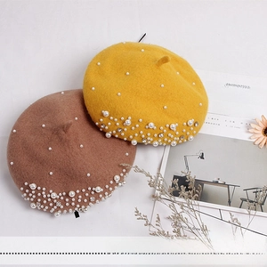 Detail of yellow and brown wool berets with pearl and rhinestone embellishments