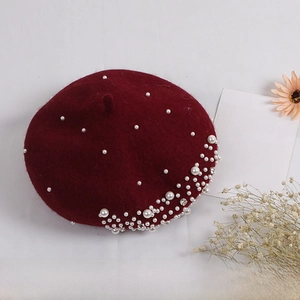 Close-up of wine red wool beret decorated with white pearls and sparkling rhinestones