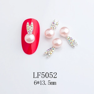 Detail of bunny nail charms with pink pearl head and colorful rhinestones on white base